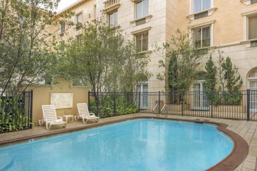 a swimming pool with two chairs and a building at Ayres Hotel Manhattan Beach in Hawthorne