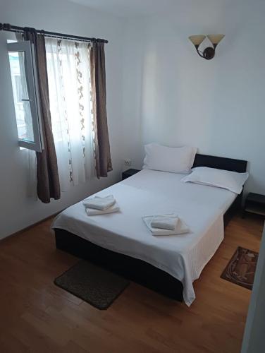 a bedroom with a bed with white sheets and a window at Casa Bibi in Costinesti