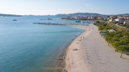 a beach with people laying on the sand and the water at Apartments Anita in Srima