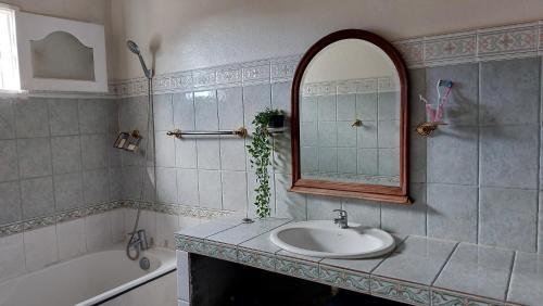 a bathroom with a sink and a mirror and a tub at Maison Créole Soalaze in Salazie