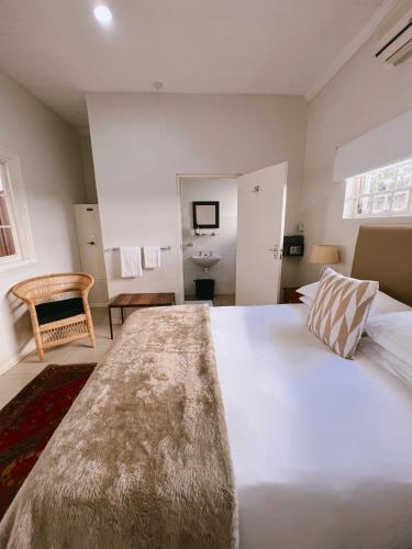 a bedroom with a large white bed and a bathroom at Ebony Lodge in Mthatha