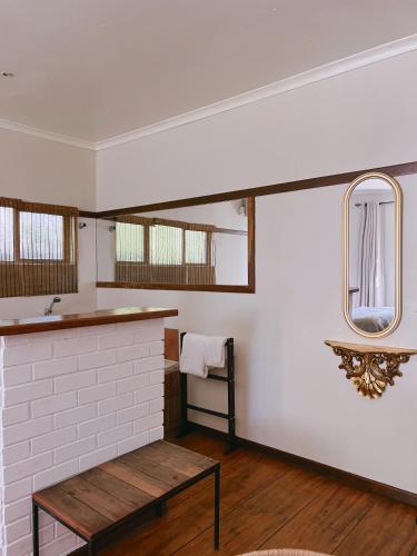 a bathroom with a sink and a mirror and a bench at Ebony Lodge in Mthatha