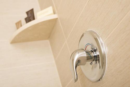 a bathroom door with a faucet on a wall at Ayres Hotel Manhattan Beach in Hawthorne