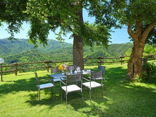 a table and chairs under a tree with a view at Apartment Azienda Agricola Piano Rosso-1 by Interhome in Marradi