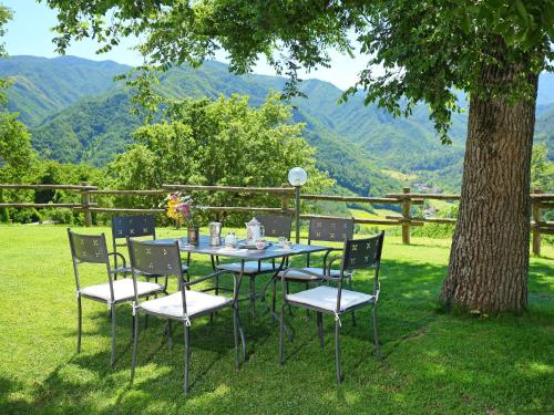 a table and chairs under a tree in the grass at Apartment Piano Rosso 1 by Interhome in Marradi