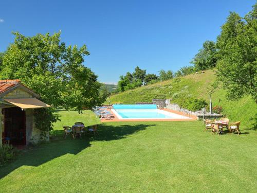 a yard with a swimming pool with tables and chairs at Apartment Piano Rosso 1 by Interhome in Marradi