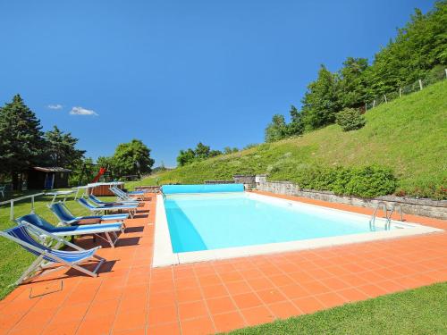 a swimming pool with lounge chairs and a hill at Apartment Piano Rosso 1 by Interhome in Marradi