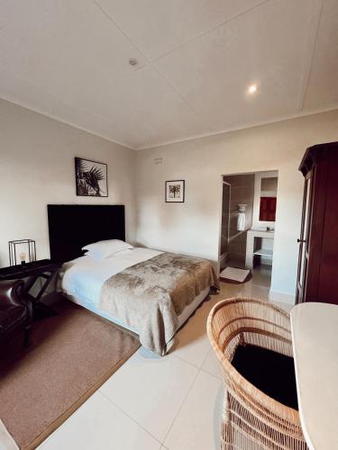 a bedroom with a bed and a table and chairs at Ebony Lodge in Mthatha