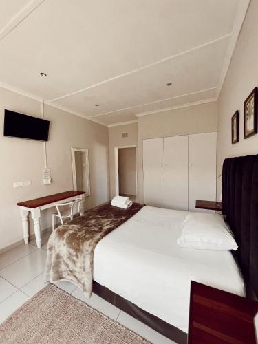 a bedroom with a large bed and a desk at Ebony Lodge in Mthatha