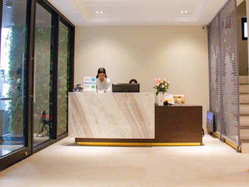 a woman sitting at a reception desk in an office at Ping Diamond Hotel Hanoi in Hanoi