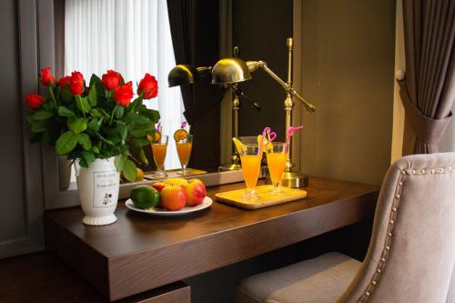 a desk with a plate of fruit and glasses of orange juice at Ping Diamond Hotel Hanoi in Hanoi