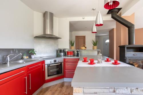 a large kitchen with red cabinets and a sink at Can Guillamou in Serralongue