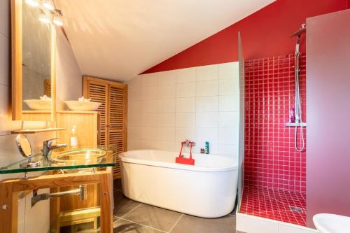 baño con bañera blanca y pared roja en Can Guillamou, en Serralongue