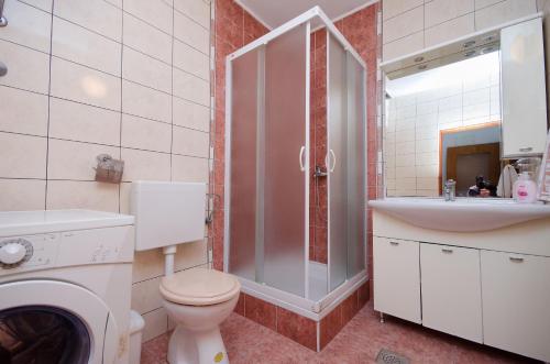 uma casa de banho com um chuveiro, um WC e um lavatório. em Apartment Marica em Lopar