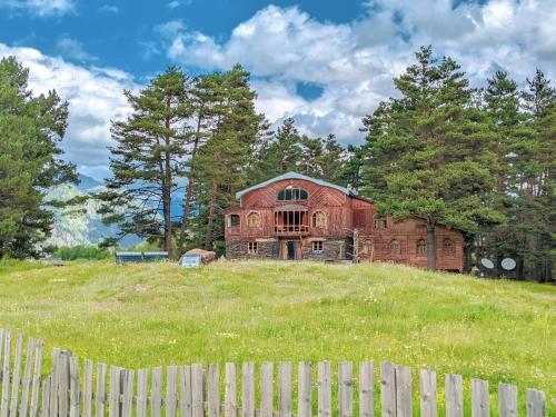 an old house on a hill behind a fence at Hotel Tusheti in Omalo