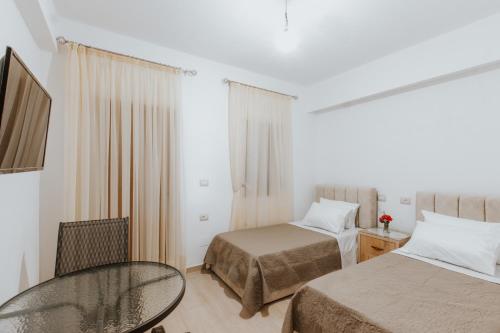 ein Hotelzimmer mit 2 Betten und einem Glastisch in der Unterkunft Panoramic Vlachos in Gjirokastër
