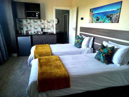 イースト・ロンドンにあるBlue Sea Guest Houseのベッド2台とキッチンが備わるホテルルームです。