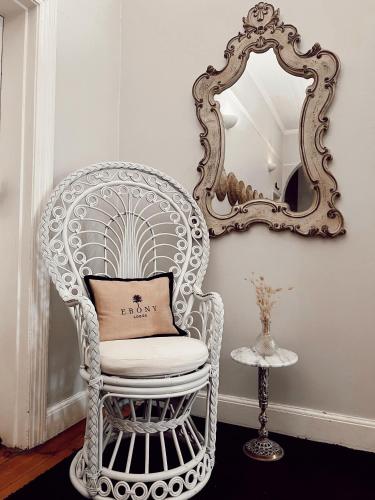 a white chair with a pillow in front of a mirror at Ebony Lodge in Mthatha