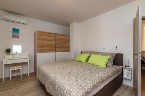 een slaapkamer met een bed met groene kussens erop bij House Villa Ivona in Suhovare