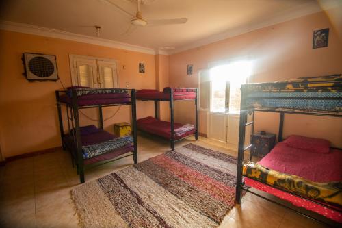 a room with three bunk beds and a rug at Go Inn Backpackers in Aswan