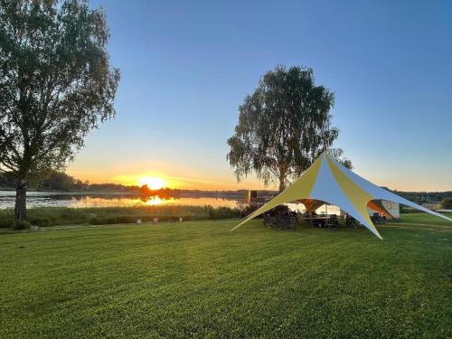 une tente dans un champ avec le coucher du soleil en arrière-plan dans l'établissement Glempings Velo Latgale, à Izvalta