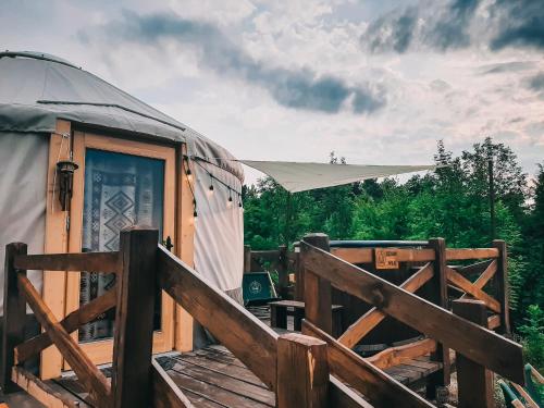 a yurt with a wooden deck and a fence at Jurty z widokiem, prywatna balia- DZIKOLAS GLAMPING in Krasnobród