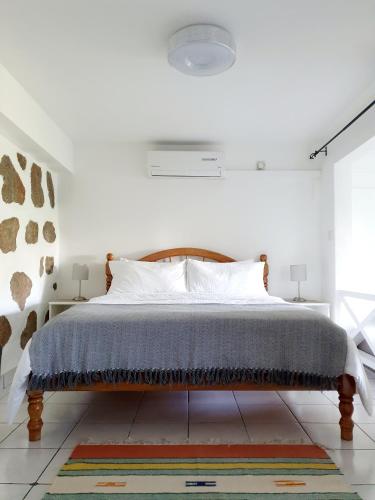 a white bedroom with a bed with a wooden headboard at Rose Self Catering in Beau Vallon