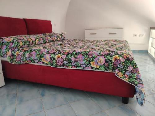 ein rotes Bett mit einer Blumendecke darauf im Schlafzimmer in der Unterkunft VisitPonza - La tana di Bacco in Ponza