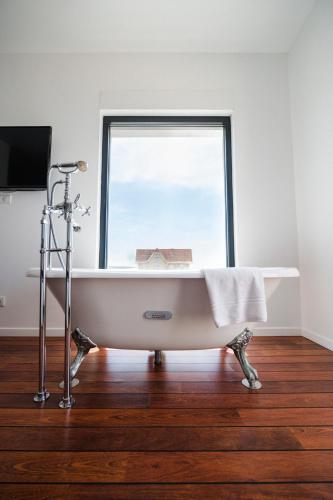 a bath tub sitting in a room with a window at Le Grand Hotel de la Plage in Biscarrosse-Plage