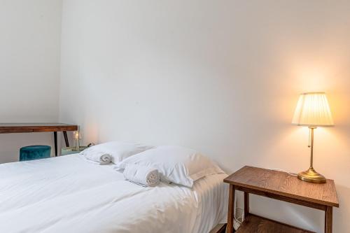 a bedroom with a white bed with a table and a lamp at Le Grain de Sable in Thionville