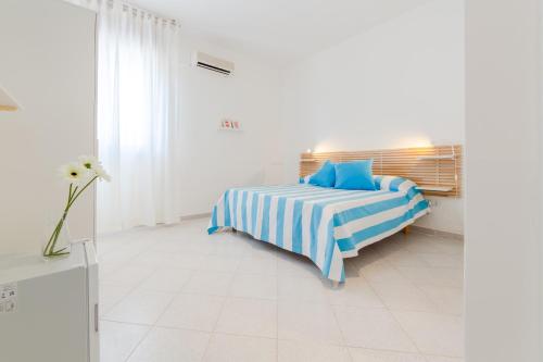 a white bedroom with a bed with blue pillows at Vidamarina - Camere al Mare in Torre Lapillo