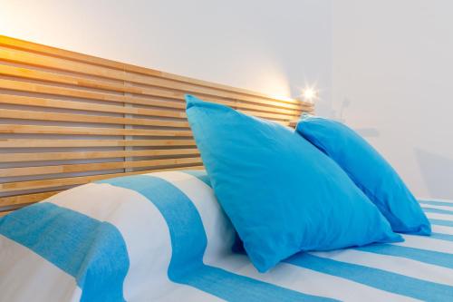 Una cama con almohadas azules y blancas. en Vidamarina - Camere al Mare en Torre Lapillo