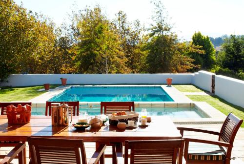 a dining table and chairs next to a swimming pool at Mitre's Edge Pool House in Klapmuts