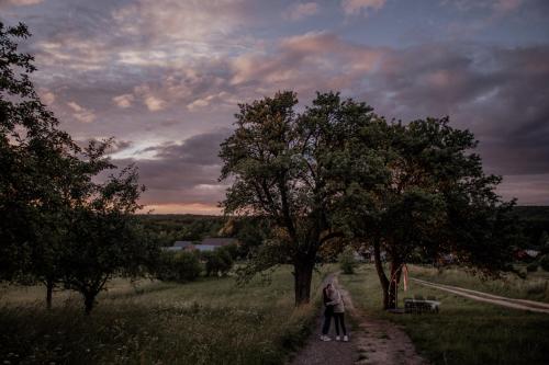 two people walking down a dirt road with trees at Jurty z widokiem, prywatna balia- DZIKOLAS GLAMPING in Krasnobród