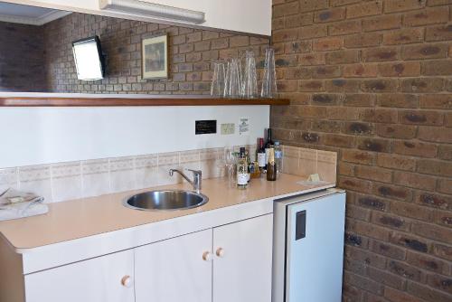 a kitchen with a sink and a brick wall at Travellers Rest Motor Inn Swan Hill in Swan Hill