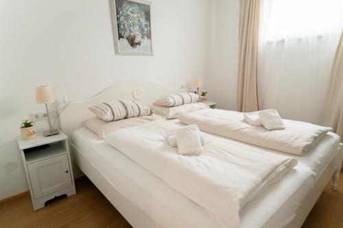 uma cama branca com lençóis brancos e almofadas em Villa Hubertus Orchidee em Kirchbach