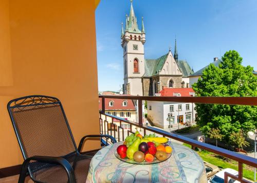 a plate of fruit on a table on a balcony with a church at Hotel Kotyza in Humpolec