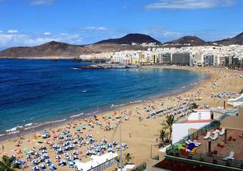 Una playa con multitud de gente y el océano. en APARTAMENTO PLAYA ALCARAVANERAS, en Las Palmas de Gran Canaria