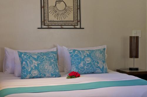 a bed with blue and white pillows and a red flower on it at Paradise Cove Resort in Naukacuvu Island