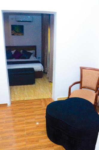a bedroom with a bed and a chair and a ottoman at J Gibson Hotel in Lagos
