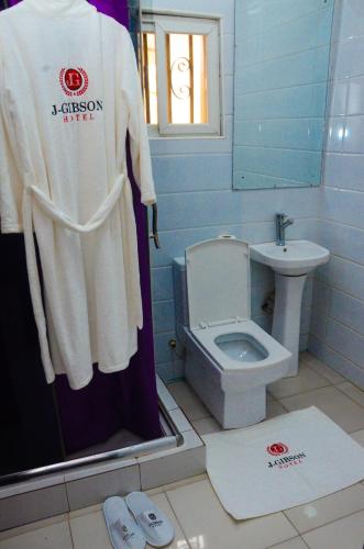 a bathroom with a toilet and a shirt on a shower curtain at J Gibson Hotel in Lagos