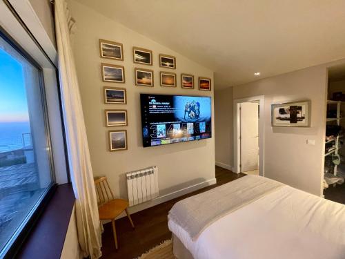 1 dormitorio con 1 cama y TV en la pared en Casa do Cruceiro surfing Costa da Morte en Cayón