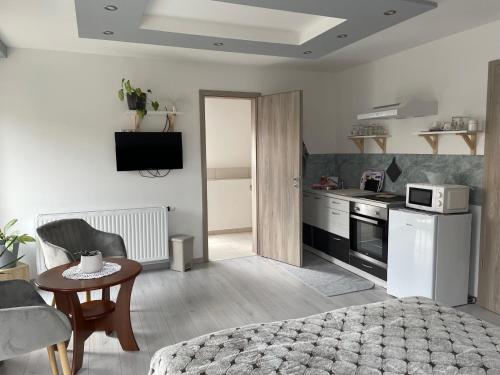 1 dormitorio con cama, mesa y cocina en Jasmin Apartment House, en Vonyarcvashegy