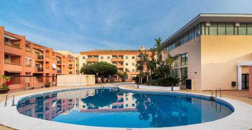 una gran piscina frente a un edificio en Apartamento junto a la playa con piscina y parking en Punta Umbría