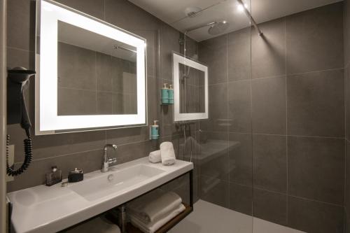a bathroom with a sink and a mirror and a shower at Novotel Antibes Sophia Antipolis in Valbonne
