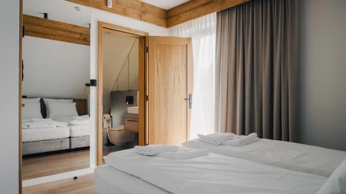 2 camas blancas en una habitación con ventana en Dolina Barw - całoroczne domki na wynajem, en Rabka