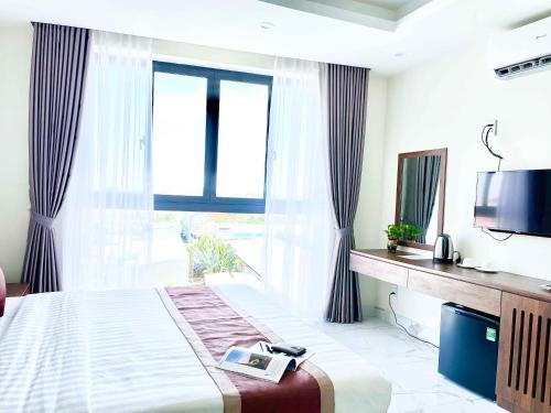 a bedroom with a bed with a tv and a window at Hoàng Triều Hotel - Marina Bình Dương in Thu Dau Mot
