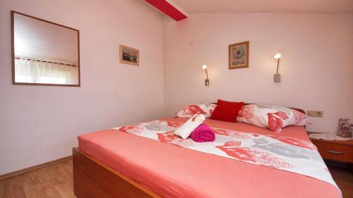 1 dormitorio con 1 cama con almohadas rojas y blancas en Apartments Malenica, en Vodice