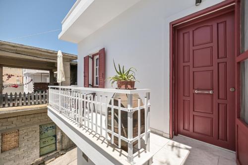 uma varanda com uma porta vermelha e um vaso de plantas em Akakia Residence - Vivlos Village em Vívlos