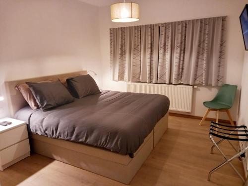 a bedroom with a bed and a green chair at Dunes et Mer - Terrace, garden and free parking space in Ostend